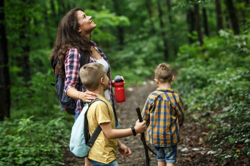 a mom roadschooling her kids in a version of RV homeschooling by hiking in the woods for science class